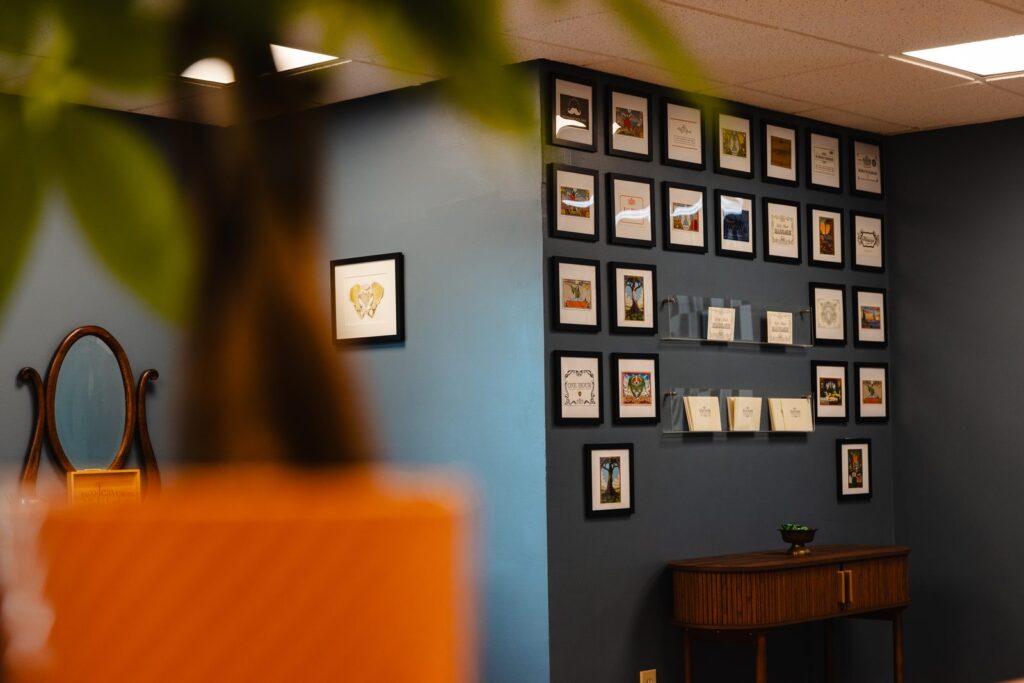 Wall of framed Bodywork Professionals gift certificate designs in the Clifton Park lobby